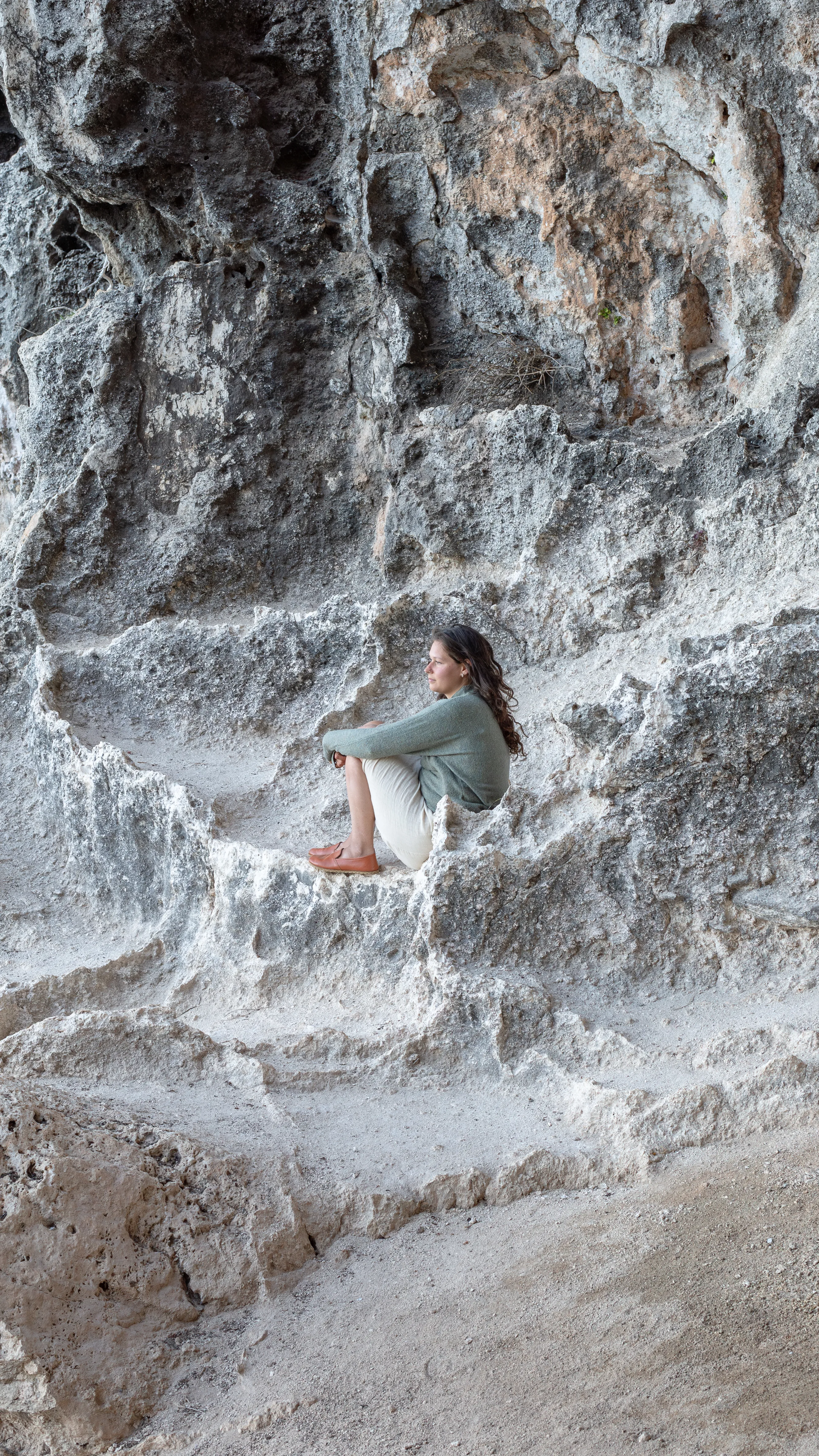 Nikita tucked into a hollow in the ancient white rock of the Salento cave, eyes closed