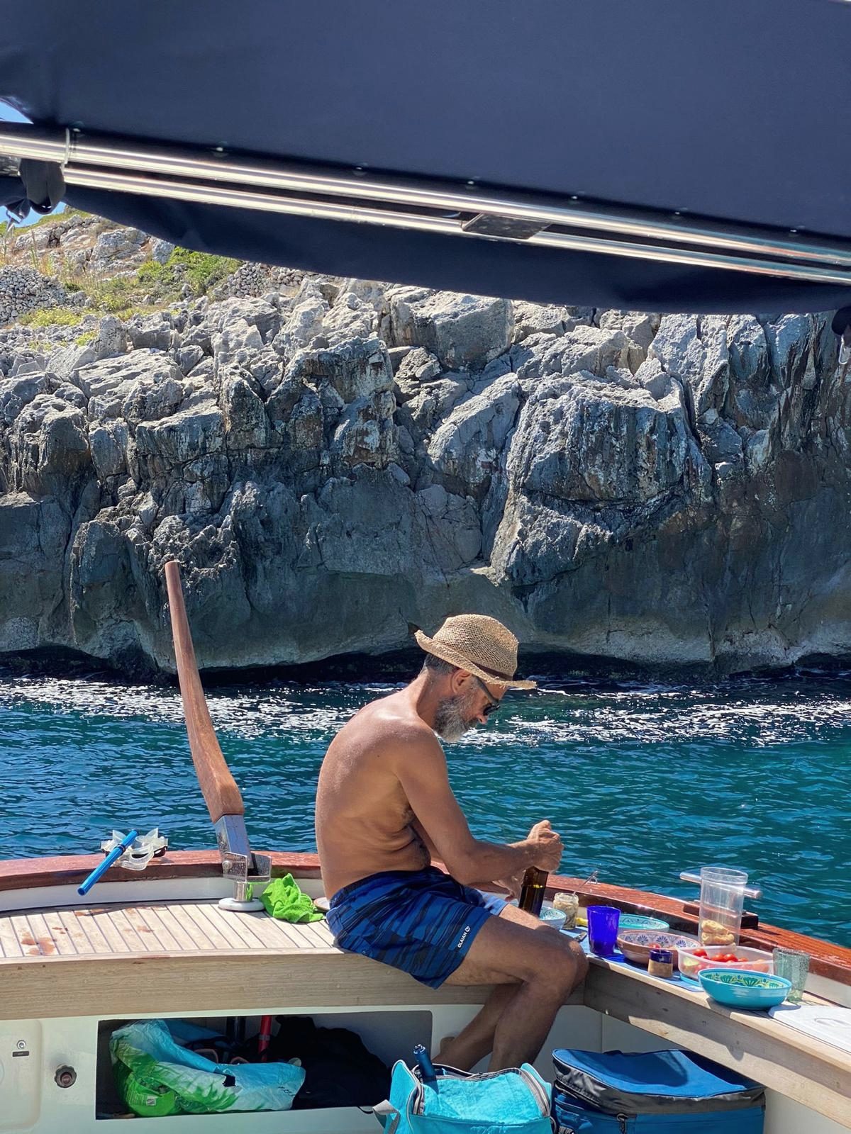 Giuseppe di Nerea Escursioni apre il vino sulla barca sotto le falesie del Salento