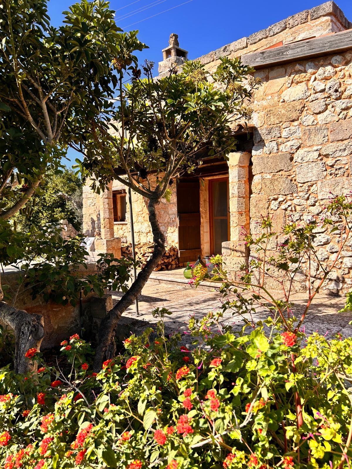 The stone house of Il Sentiero among flowering plants and green