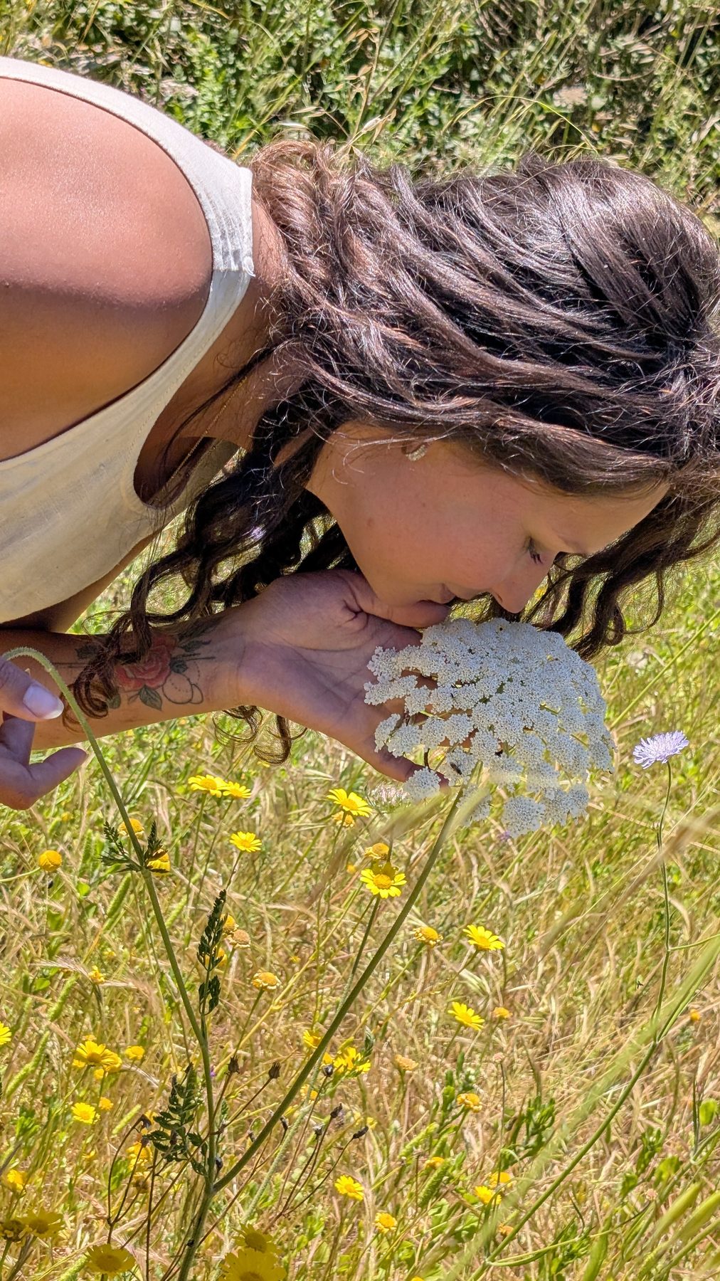Nikita smelling a white wildflower in a Salento meadow