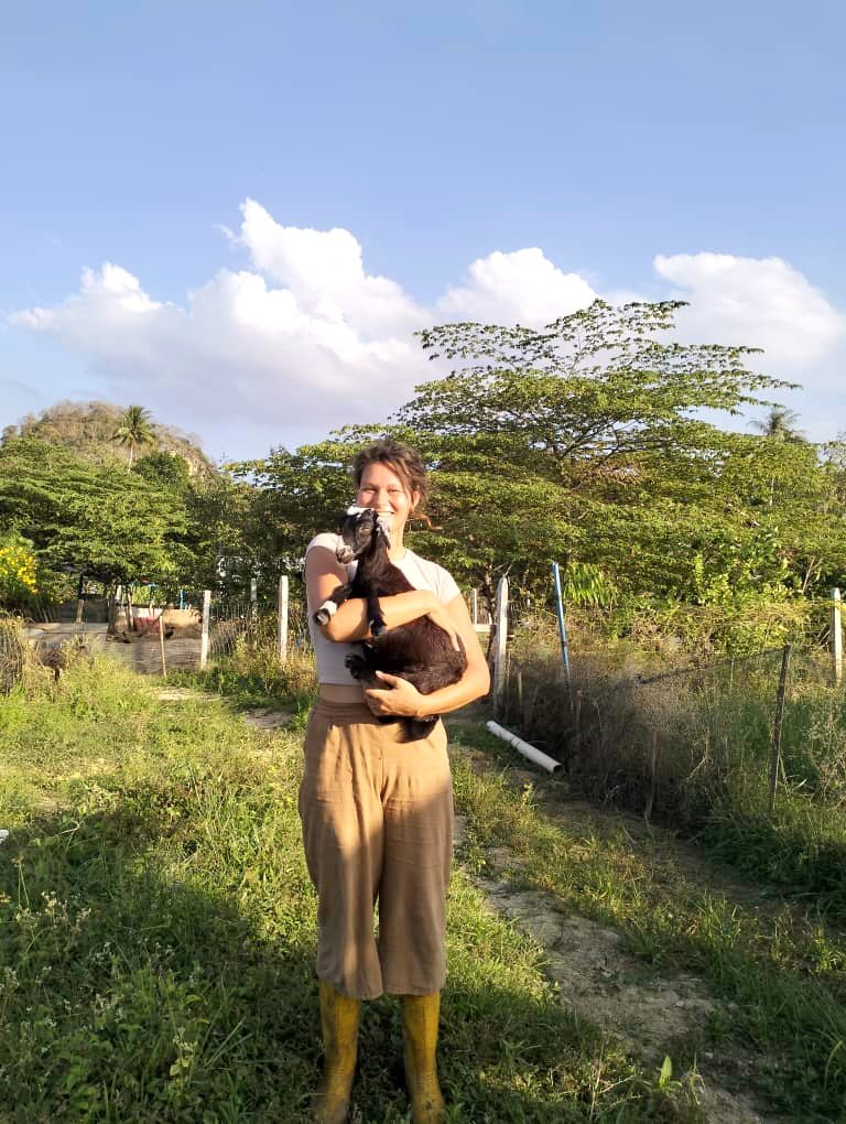 Nikita holding a baby goat on an organic farm in Malaysia