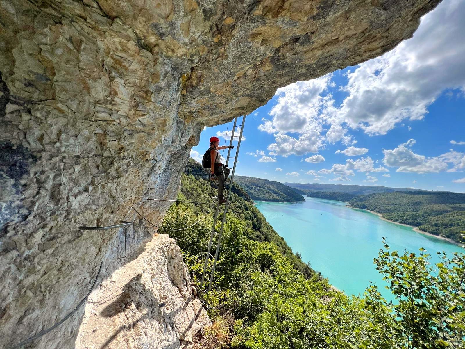 Nikita rock climbing via ferrata with turquoise river below