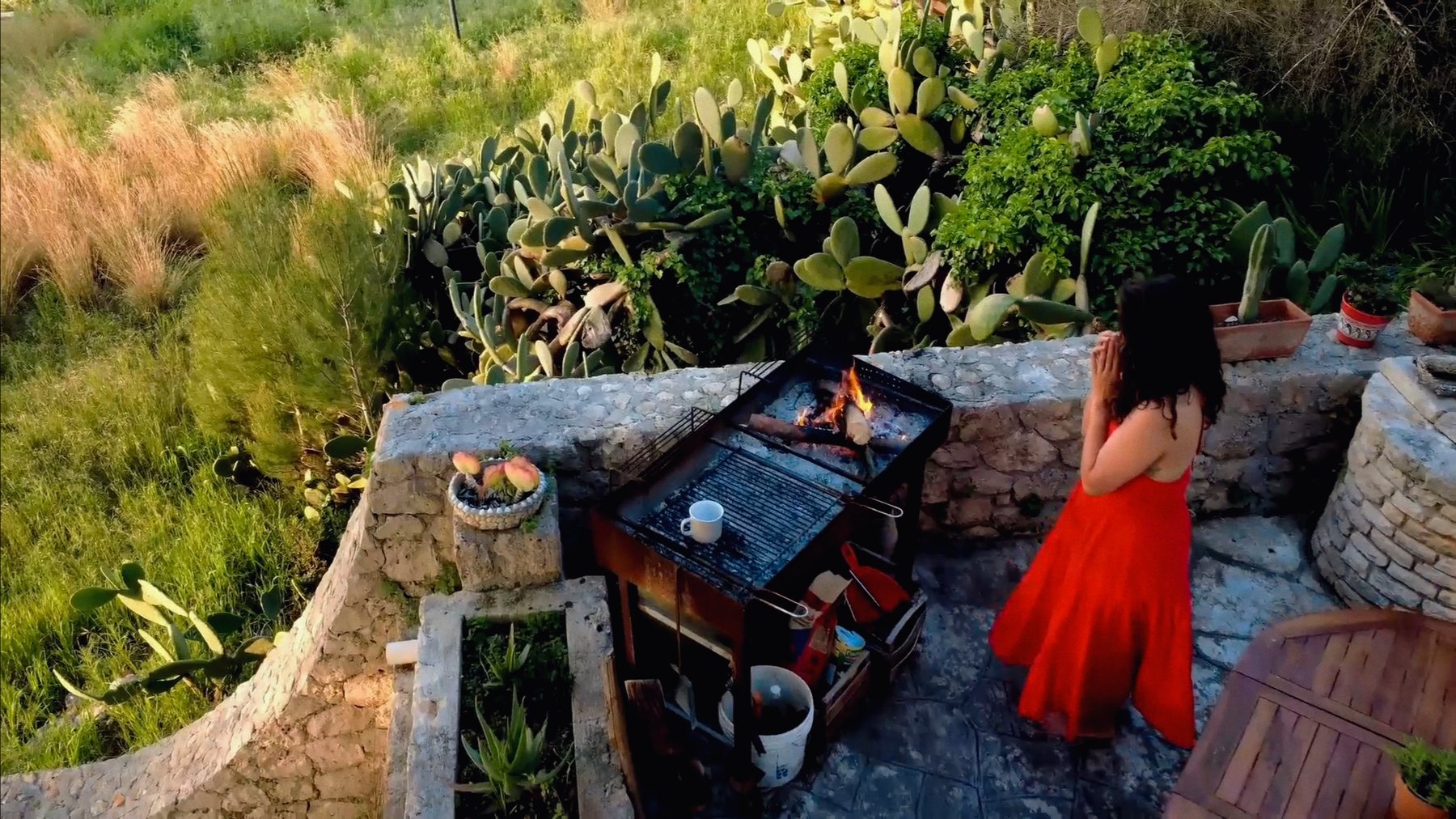 Nikita standing with her hands together in front of the fire on the terrace at Il Sentiero, Salento