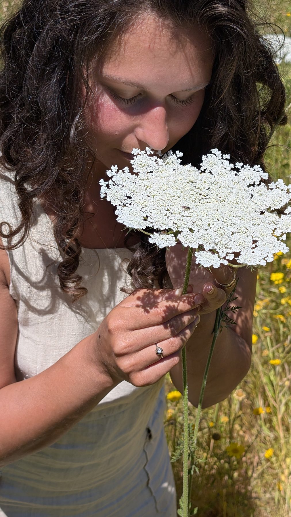 Nikita smelling a white wildflower in Salento with eyes closed