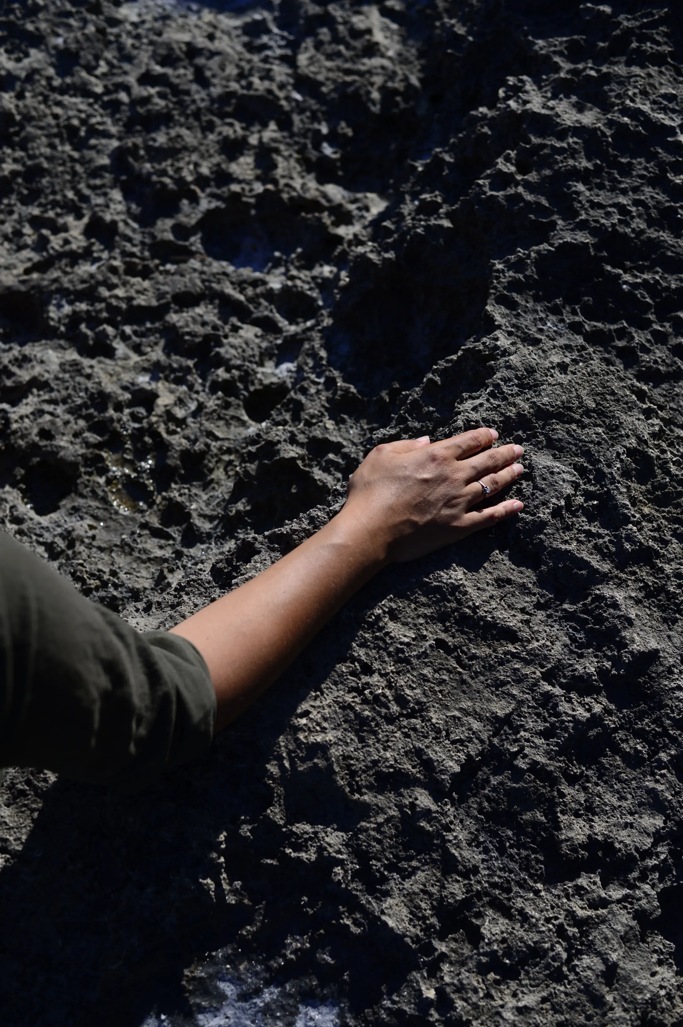 Nikita's hand touching the Salento limestone rock by the sea