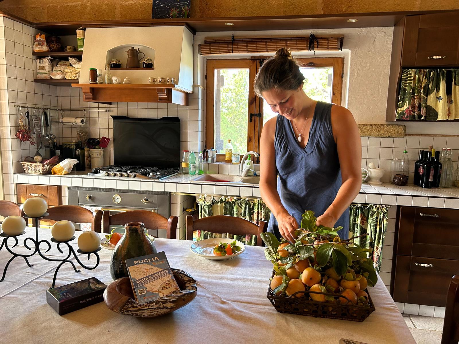 Nikita arranging fresh persimmons on the kitchen table at Il Sentiero