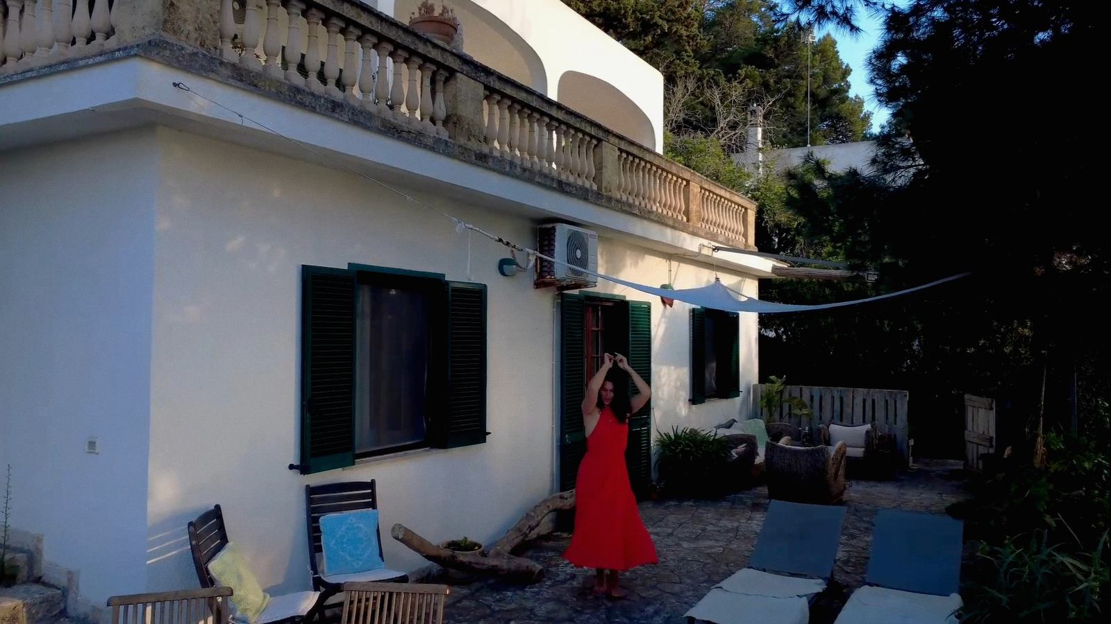 Nikita in abito rosso sul terrazzo della villa nella luce della sera